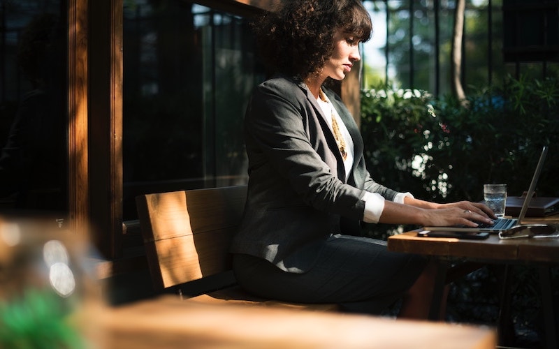 Female professional sitting outdoors, studying on laptop